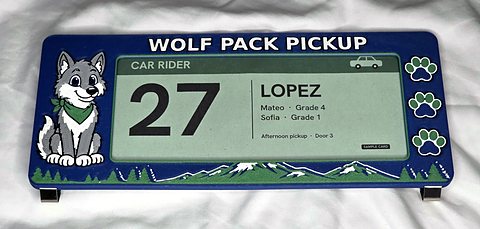The Wolf Pack car line card holder, flat: navy frame, the wolf, three paw prints, mountains along the bottom, and a green sample card in the window.