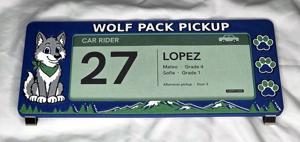 The Wolf Pack car line card holder, flat: navy frame, the wolf, three paw prints, mountains along the bottom, and a green sample card in the window.