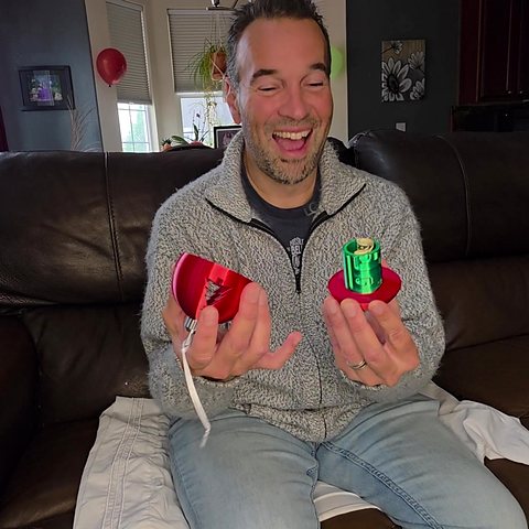 Enrique laughing as the ornament opens and the rolled cash comes out.