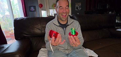 Enrique laughing as the ornament opens and the rolled cash comes out.