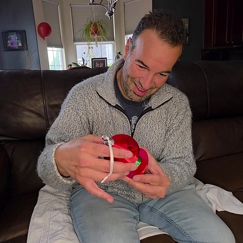Enrique on the couch, turning the red Christmas Money Puzzle Ornament to solve the maze.